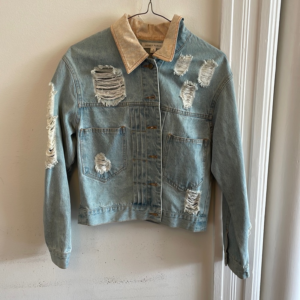 Cute ripped style jean jacket with holes and collar with designs.